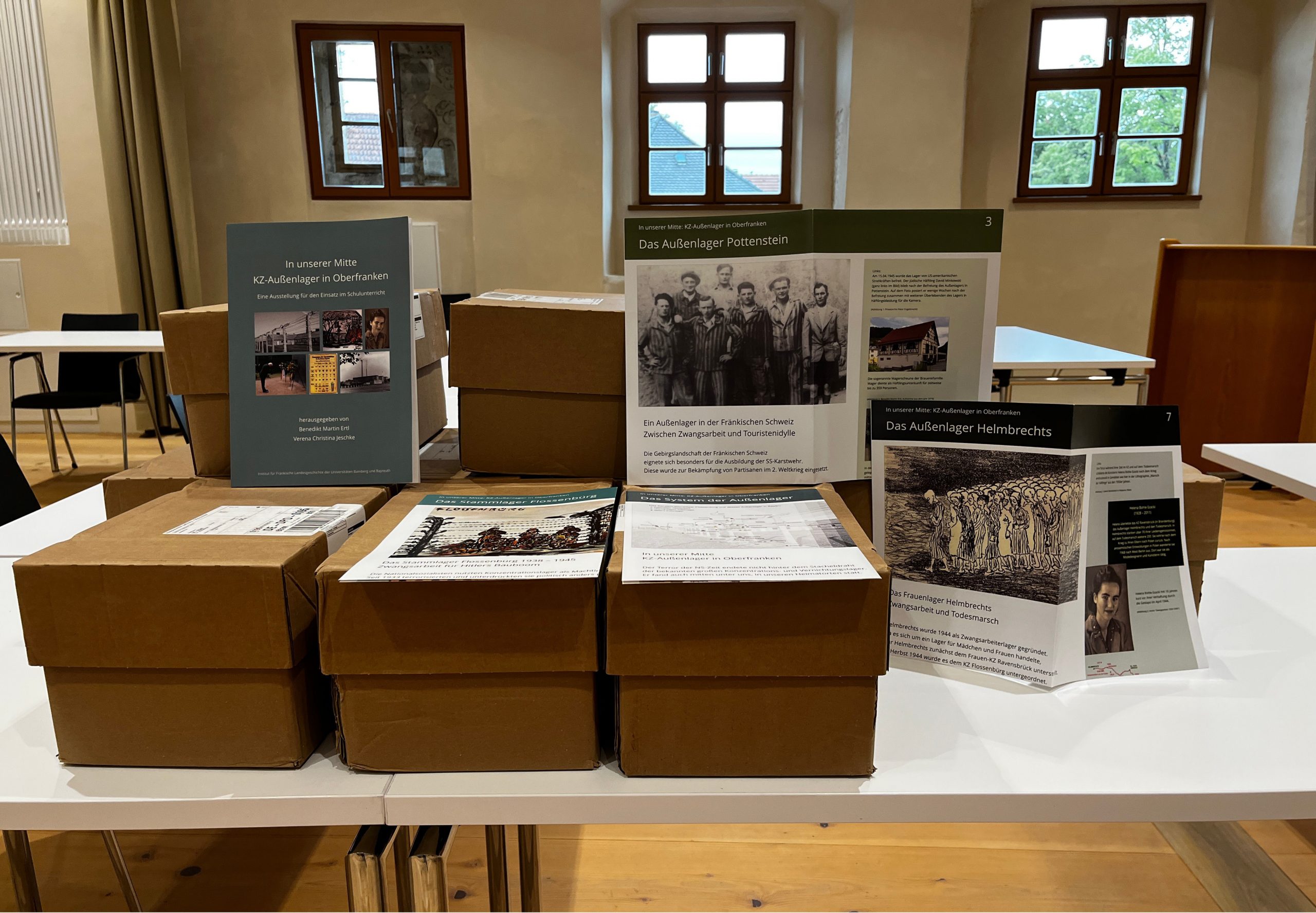 Kartons mit Ausstellungen "In unserer Mitte" auf einem Tisch